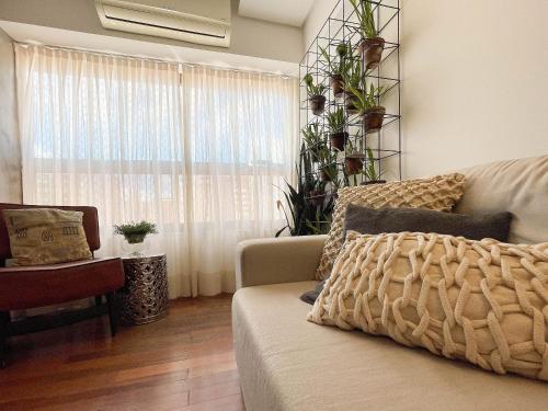 a living room with a couch and a window with plants at Brisas do Cabo Branco by Hosppedar in Tambaú