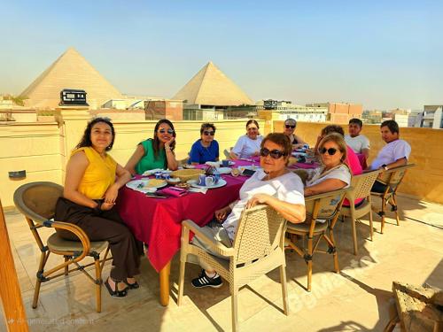 a group of people sitting at a table in front of pyramids at Pyramids & SphinX Grand Hotel in Cairo