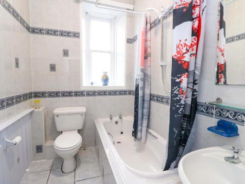 a bathroom with a toilet and a tub and a sink at 9A Market Square in Stonehaven