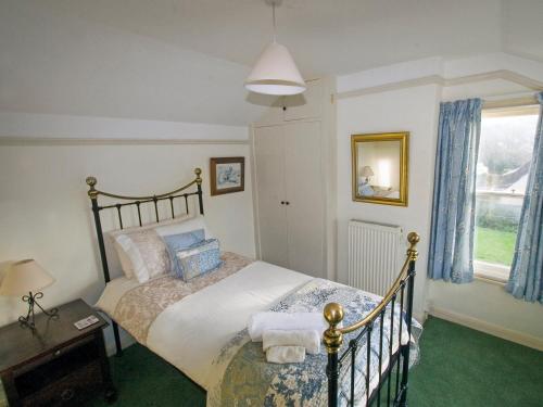 a bedroom with a bed and a window at Swiss Cottage in Chideock
