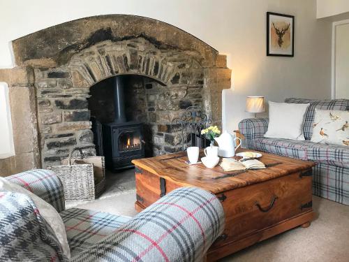 a living room with a stone fireplace and a coffee table at Lightfoot House in Redmire