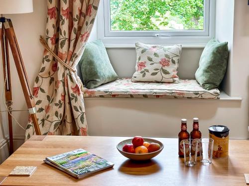a table with a bowl of fruit and a window seat at The Owlery At Aysgarth in Aysgarth