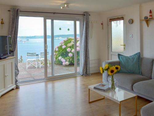 a living room with a couch and a large sliding glass door at Breakwater View in Turnchapel