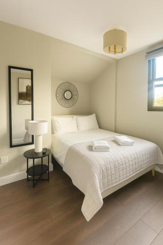 a white bedroom with a bed and a lamp at City Centre GuestHouse By Luxiety Stays Cambridge Perfect For Families With Affordable Rates in Cambridge