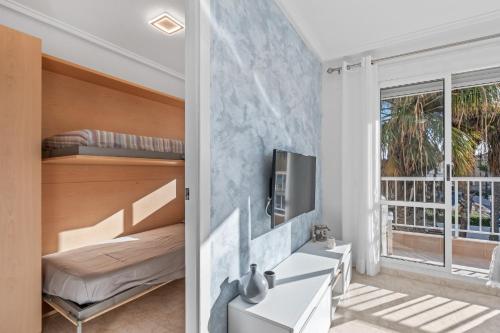 een slaapkamer met een bed en een bureau met een tv bij Pleamar 23 in Torrevieja