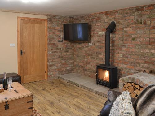a living room with a brick wall with a fireplace at The Old Forge in Burshill