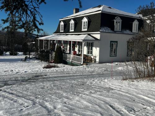 een zwart-wit huis in de sneeuw bij Auberge musicale Pour un Instant in La Malbaie