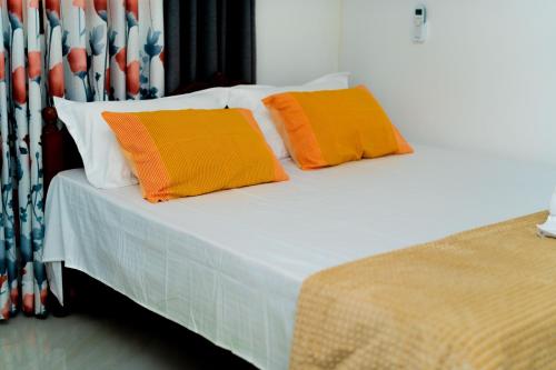 a bed with two orange pillows on it at Shasha House Bentota in Hettiwatta