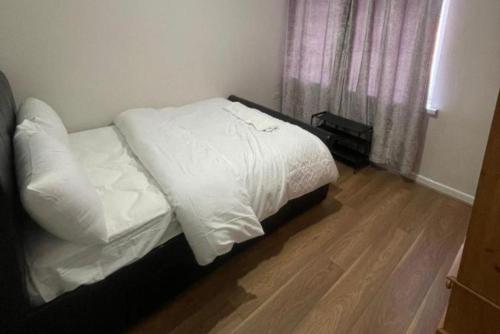 a bedroom with a bed with white sheets and a window at Hillside Retreat in Wolverhampton in Wolverhampton