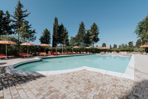 a large swimming pool with chairs and umbrellas at Hotiday Toscana Riparbella in Riparbella