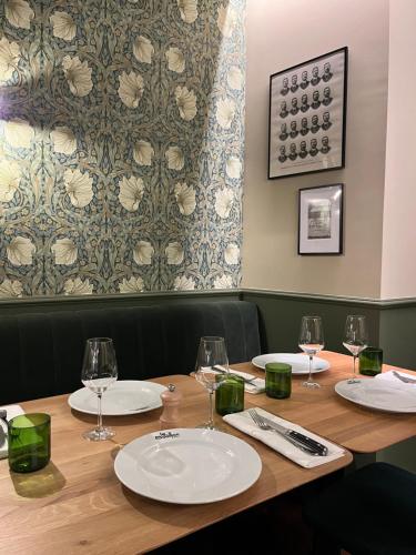 a wooden table with plates and wine glasses on it at Studios et Appartement meublé de tourisme in Altkirch