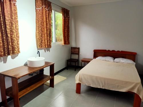 une chambre avec un lit, un lavabo et une fenêtre dans l'établissement Bovenhuis Masusa, à Paramaribo