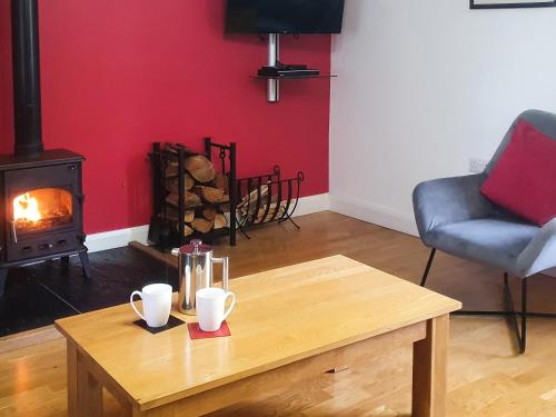 a living room with a table and a wood stove at Stabl-Oh4 in Dihewid