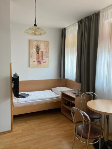a small room with a bed and a table and chairs at Penzion U Radnice in Kyjov