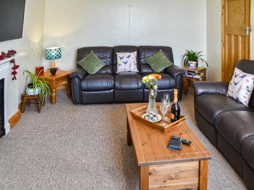 a living room with a leather couch and a coffee table at St Judes in Mundesley
