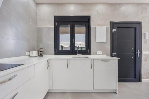 eine weiße Küche mit Spüle und Fenster in der Unterkunft Villa Infinity 1 in Chiclana de la Frontera