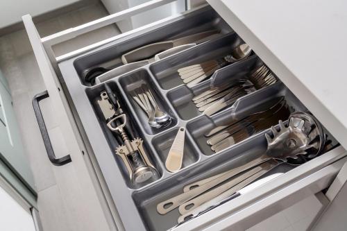 een lade in een koelkast gevuld met keukengerei bij Design Green Garden Apartments with Private Parking & Playground in Rīga