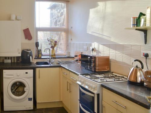 a kitchen with a stove and a washing machine at Marley's Retreat in Seaton Delaval