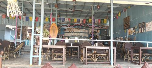 ein Restaurant mit Tischen und Stühlen in einem Raum in der Unterkunft Nirvana Beach Cottages in Canacona