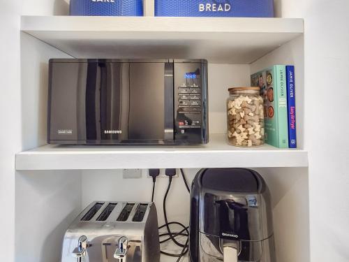 a microwave on a shelf with a toaster and a coffee maker at The Colleys in Lechlade