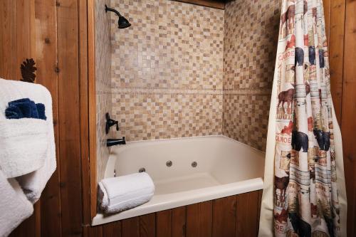 a bathroom with a bath tub with a shower curtain at Cozy, secluded 2BR cabin with hot tub & pool table only 1 mile from PF parkway! in Pigeon Forge