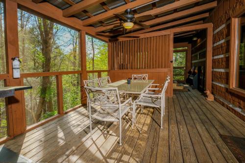 a wooden deck with a table and chairs on it at Cozy, secluded 2BR cabin with hot tub & pool table only 1 mile from PF parkway! in Pigeon Forge