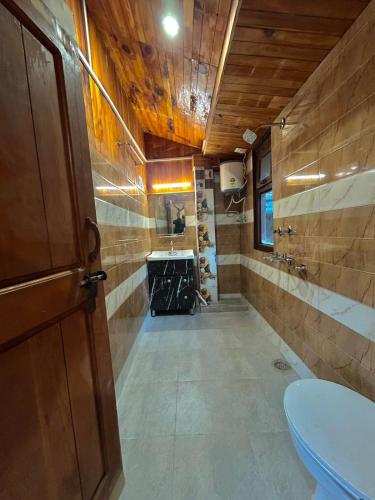 a bathroom with a toilet and a sink in it at Alpine Stays Riverside in Jibhi