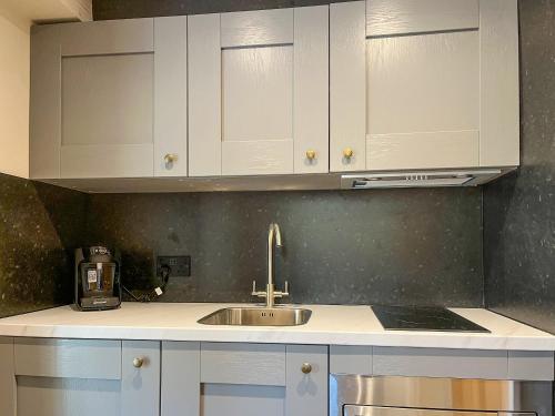 a kitchen with white cabinets and a sink at Studio On The Green - Uk48298 in Chinley