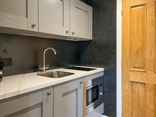 a kitchen with white cabinets and a sink at Studio On The Green - Uk48298 in Chinley