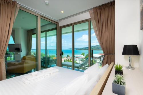 ein Schlafzimmer mit Bett und Blick auf das Meer in der Unterkunft Modern condo with full sea view, 4 min walk to Kamala beach in Kamala Beach