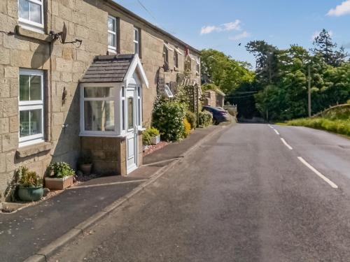 an empty street in front of a house at Beech Cottage in Hepple