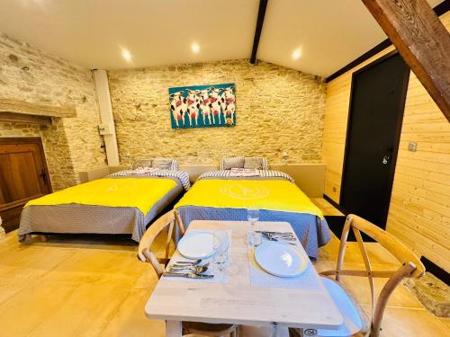 two beds in a room with a table and chairs at Chez Vivi in Gindou