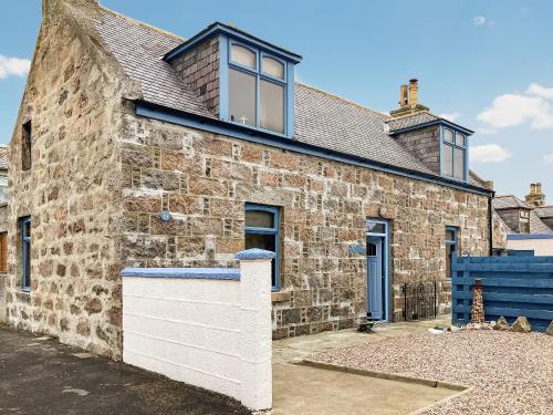 a stone house with a blue fence in front of it at Going Coastal in Inverallochy