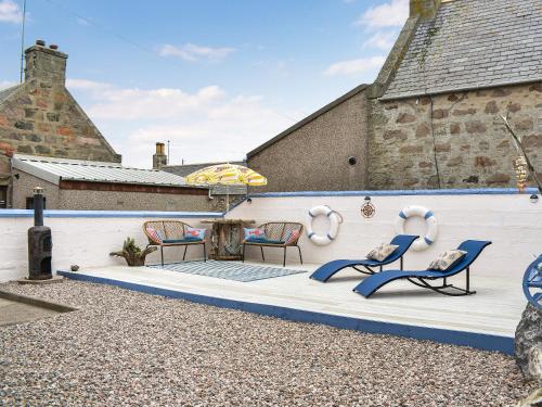 a group of chairs and an umbrella on a patio at Going Coastal in Inverallochy