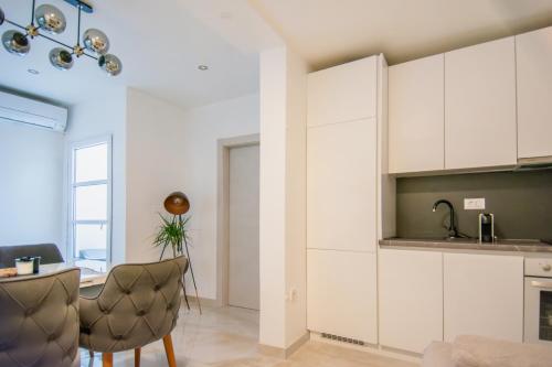 a kitchen with white cabinets and a table and a chair at Apartman Kala-Two bedroom-Terrace in Sutivan