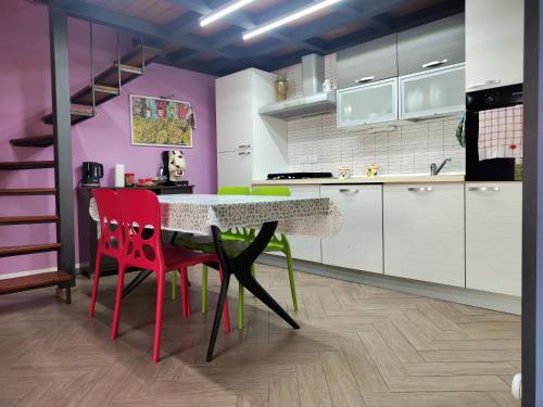 Eine Küche mit einem Tisch, roten Stühlen und lila Wänden in der Unterkunft Donna Lucia in Giardini-Naxos