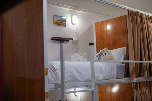 a bedroom with a bunk bed with white sheets at Sanga Rooftop Hostel in Pakse