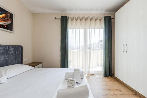 a bedroom with a white bed and a large window at Luma Penthouses by Kondo Stays in Tirana