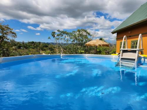 a blue swimming pool with a chair and a house at Casa Campo Obymar/vista panorámica/piscina privada in Moca