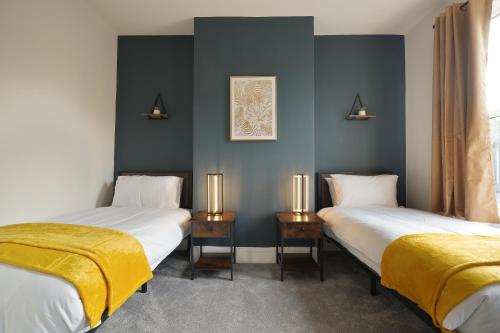 two beds in a room with blue walls at 3-Bed Home Perfect for Exploring Nottingham & Derby in Long Eaton