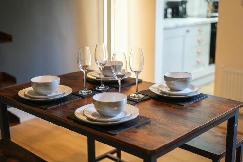 a wooden table with wine glasses and plates on it at 3-Bed Home Perfect for Exploring Nottingham & Derby in Long Eaton