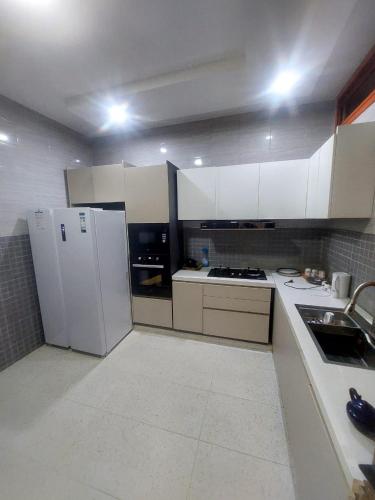 una cucina con mobili bianchi e un frigorifero bianco di Appartement paisible a Dakar