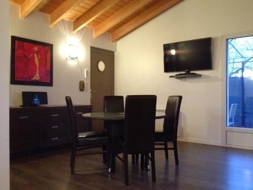 a dining room with a table and chairs and a flat screen tv at CotiLoft - Appartement Terrasse Climatisé au cœur de La Cotinière in La Cotinière