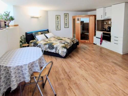 a bedroom with a bed and a table with chairs at Studio 40 m2 avec sauna proche de Strasbourg in Mittelhausbergen
