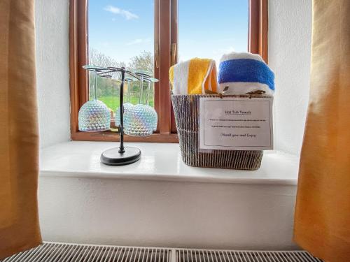 a window sill with a basket of towels and a thermometer at Wild Rose in Delabole