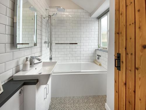 a bathroom with a white tub and a sink at Wild Rose in Delabole