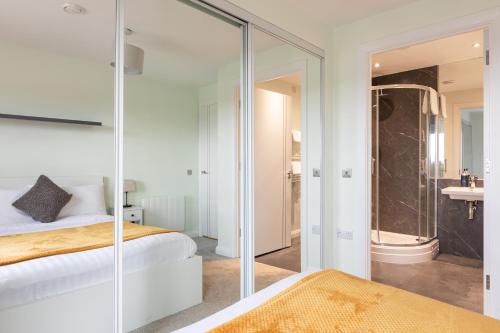 a bedroom with a glass door leading to a bathroom at Stylish 2-Bed Penthouse Sleeps 6 Central Location in Belfast