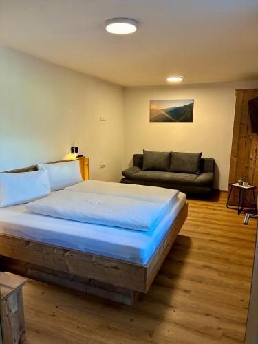a bedroom with a large bed and a couch at Apart Anton in Hainzenberg