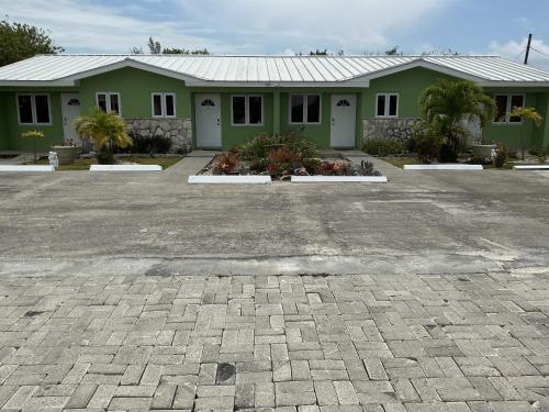 a green house with a driveway in front of it at Jubilee Gardens Freeport in Freeport