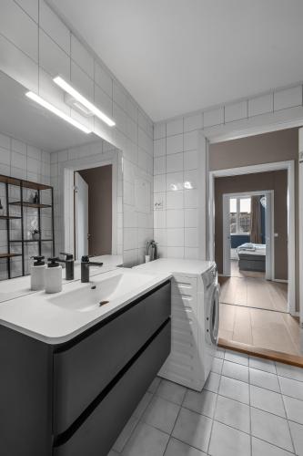 a bathroom with a sink and a washing machine at Northstay - Tromsø Harbor Mountain View Apartment in Tromsø